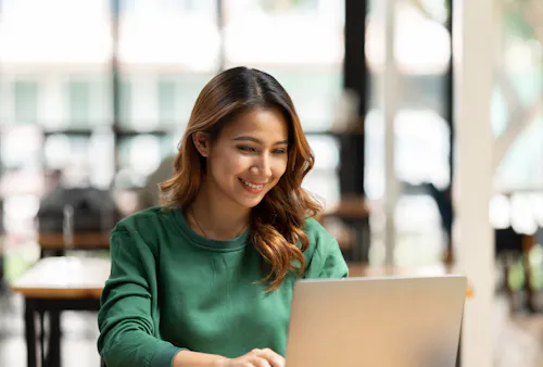 Woman in green smiling at her laptop